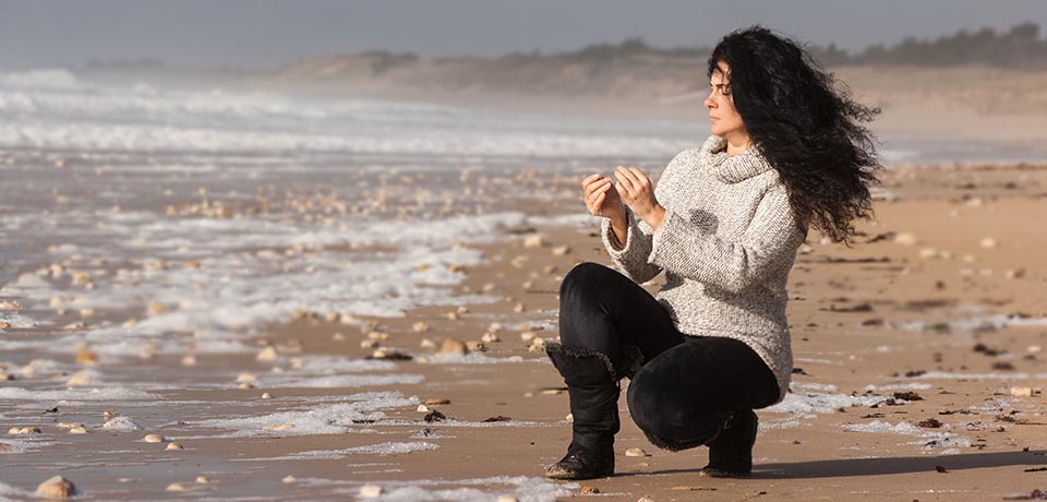 Mayka Kaïma recogiendo piedras en la playa para realizar sus cuadros de piedras